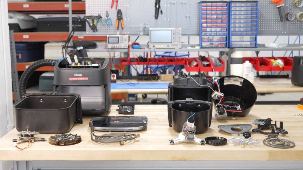 Two disassembled air fryers, exposing their food baskets, heating elements, and fans.